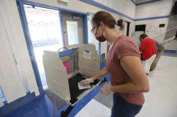 A California poll worker sanitizes a voting booth following its use at a Voter Assistance Center in Davis, CA during the 2020 General Election. Photo: Owen Yancher / Wikimedia